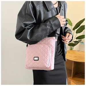 Close-up of pink quilted crossbody bag showing double zipper pockets and metal nameplate