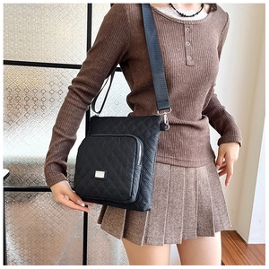 Detail of a black quilted crossbody bag showing the diamond stitch and adjustable strap