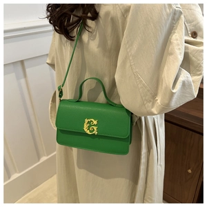 Detail of green leather handbag showing lychee texture and gold metal G buckle on the flap