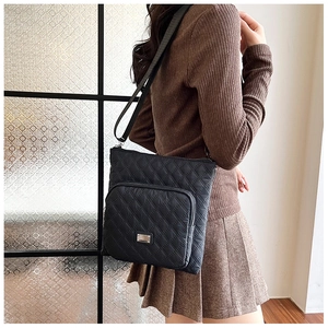 Close-up of black quilted nylon crossbody bag with zipper pocket and adjustable strap