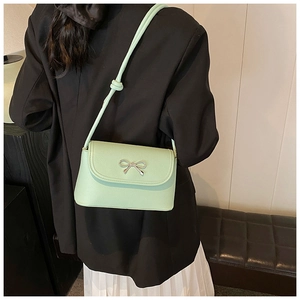 Close-up detail of the mint green underarm shoulder bag with silver bow decor on model.