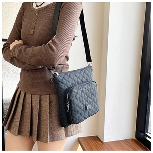 Close-up of black quilted nylon crossbody bag with adjustable strap and front zipper pocket