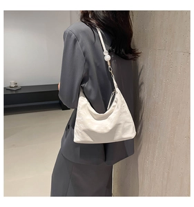 Detail of cream hobo bag with slim shoulder strap and decorative white beads