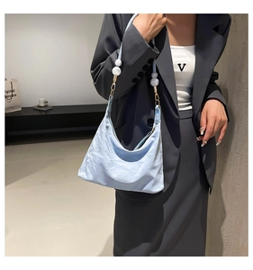 Close-up of light blue pleated nylon shoulder bag with white beads and gold buckles