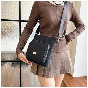 Detail of black quilted nylon crossbody bag with diamond stitching and adjustable strap