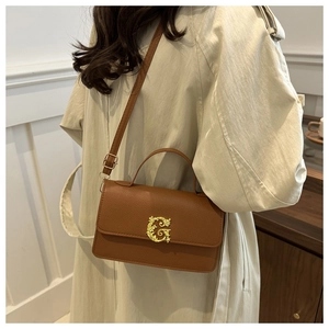 Detail of dark brown lychee leather crossbody bag with golden floral G-logo and top handle