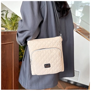 Detail shot of a beige quilted crossbody bag featuring a classic rhombus stitch pattern