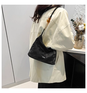 Detail of black pleated shoulder bag featuring amber bead accents and Classic text logo