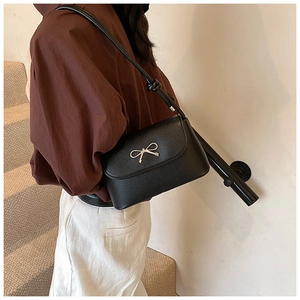 Chic black underarm shoulder bag for women with elegant metal bow detail and sleek strap.
