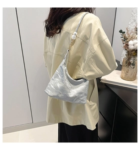 Detail of silver pleated tote bag featuring unique metallic texture and pearl strap accents