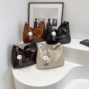 Detail of hobo shoulder bags in four colors with plush charms and wide straps