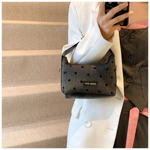 Detail of grey denim handbag with black polka dots and embroidered bow decorations