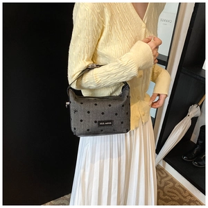 Detail of grey polka dot tote bag with rich rabbit metal logo and black leather strap