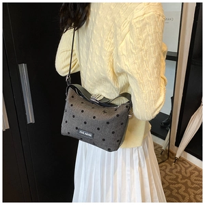 Close-up of grey polka dot bag with black bow details and leather shoulder strap