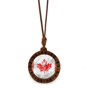 Macro detail of vintage wooden Canada flag pendant with intricate carved scrollwork frame