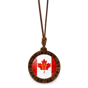 Detailed view of round wooden Canada maple leaf pendant with spiral carvings and brown cord