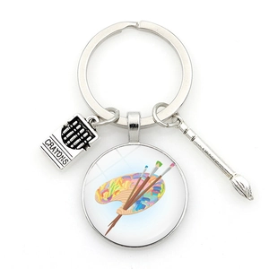 Close-up of artist palette keychain with glass cabochon, brush and crayon charms