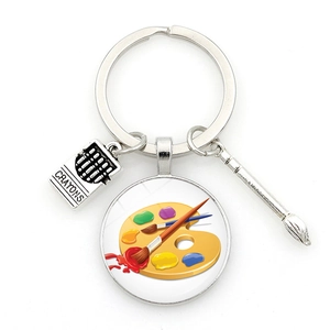Artistic keychain featuring a crayon box, color palette, and paintbrush charms