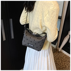 Detail of grey polka dot crossbody bag featuring a black bow and rich rabbit label