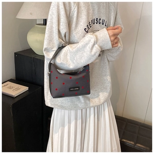 Detail of grey canvas pea bag with red polka dots and rich rabbit label worn by model