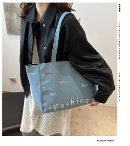 Detail of light blue denim tote bag with red Mon print shown on a female model