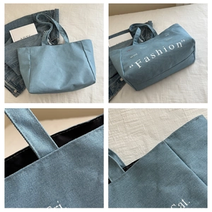 Close-up of blue denim tote bag featuring fashion print and durable handle stitching