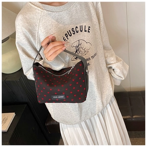 Close-up of black hobo bag featuring red heart patterns and a rich rabbit leather tag