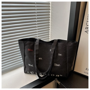Detail of black canvas tote bag showing fashion print and durable white stitching