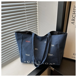 Detailed close-up of dark denim tote bag with vintage fashion and weekday printing