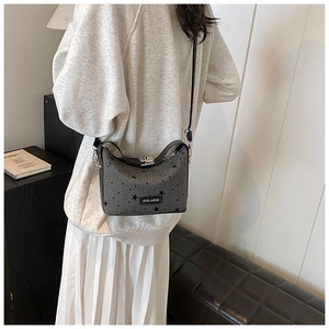 Detail of dark grey canvas crossbody bag with black star prints and silver metal lock