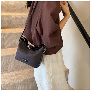 Detail of dark gray polka dot canvas crossbody bag with red patterns and leather strap