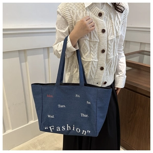 Detail of blue denim tote bag with daily week print and Fashion text on model