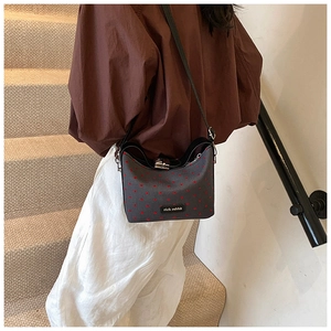 Detail of grey bucket bag with red dots and Rich Rabbit logo on indoor stairs