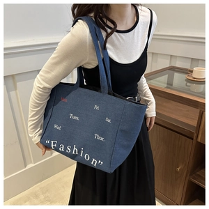 Lifestyle shot of large denim tote bag featuring weekly schedule print and fashion text