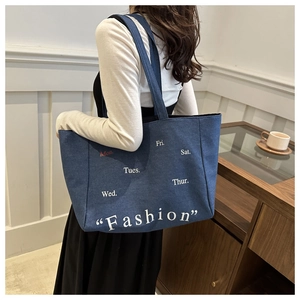 Blue denim tote bag with fashion typography lettering shown in a stylish lifestyle setting