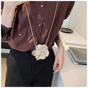Detail of a silver flower-shaped mini bag accessory with polished metallic finish and chain