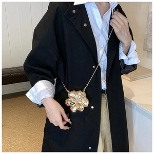 Detailed view of 3D gold flower petal clutch bag with fine metal chain on a model
