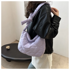 Close-up of light purple quilted handbag with heart embroidery and knotted shoulder strap