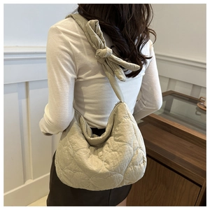 Detail of light beige quilted heart nylon hobo bag with unique decorative strap knot