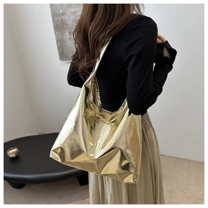 Metallic gold liquid hobo tote bag shown on model in a minimalist modern interior