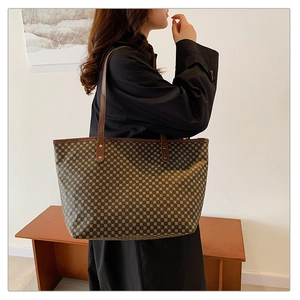 Macro view of geometric grid pattern and brown leather straps on large tote bag
