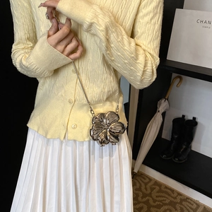 Silver flower-shaped mini chain bag with metallic finish shown on a model