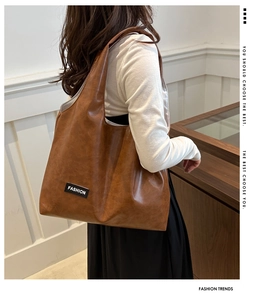 Detail of a brown PU leather hobo tote bag featuring a black FASHION logo patch