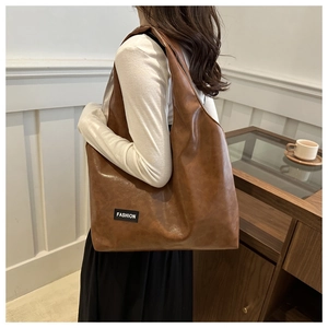 Detail of vintage oil wax leather tote bag featuring a black Fashion logo side tag