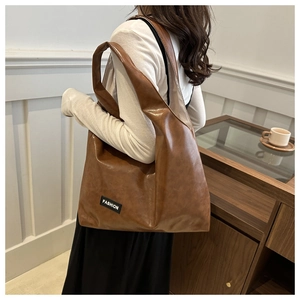 Close-up of vintage brown PU leather tote bag with wide strap and fashion label