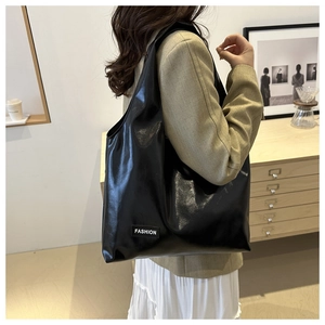 Glossy black PU tote bag with FASHION label shown on shoulder in indoor setting