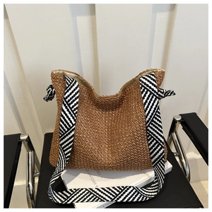 Nahaufnahme der braunen Strohtasche mit modischem schwarz-weißem geometrischem Gurt