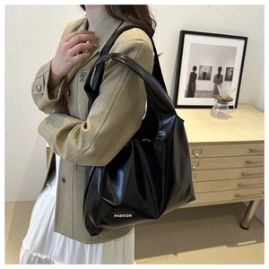 Detail of a shiny black PU leather shoulder bag featuring a fashion woven logo label