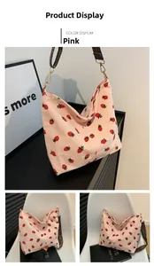 Detail of pink corduroy bucket bag with red strawberry embroidery and ethnic woven strap