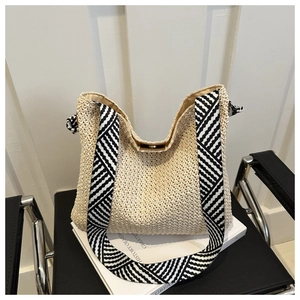 Detail der handgeflochtenen Strohtasche mit schwarz-weißem geometrischem Schultergurt